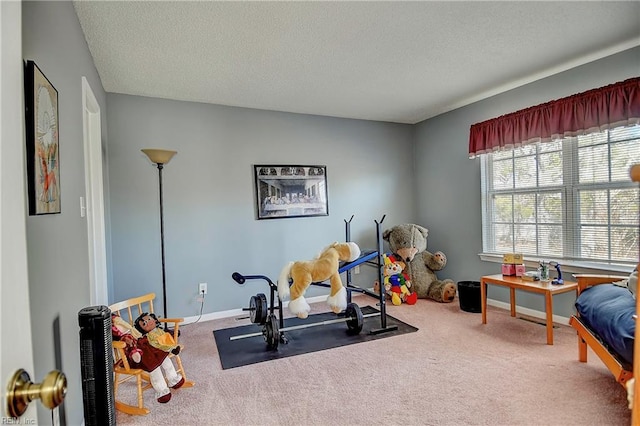 exercise room with carpet floors, baseboards, and a textured ceiling