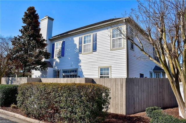 view of side of home with a chimney and fence