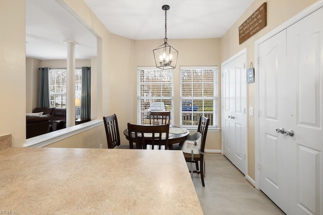 dining space featuring an inviting chandelier, decorative columns, and a wealth of natural light