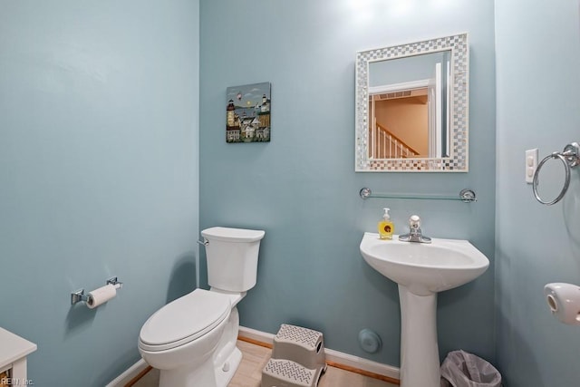 half bathroom featuring toilet and baseboards