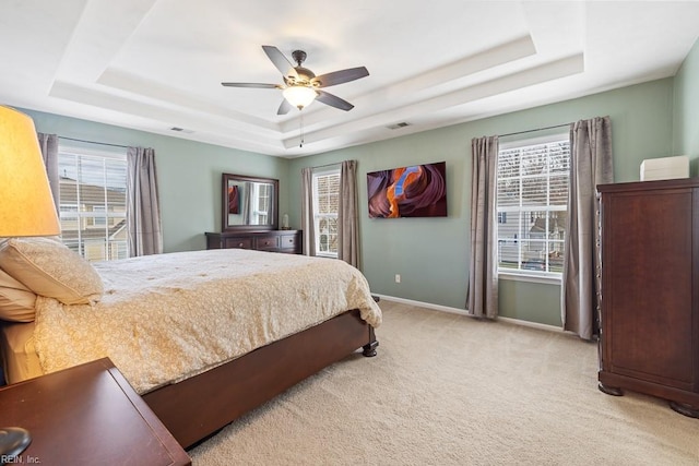 bedroom featuring baseboards, a tray ceiling, multiple windows, and light colored carpet