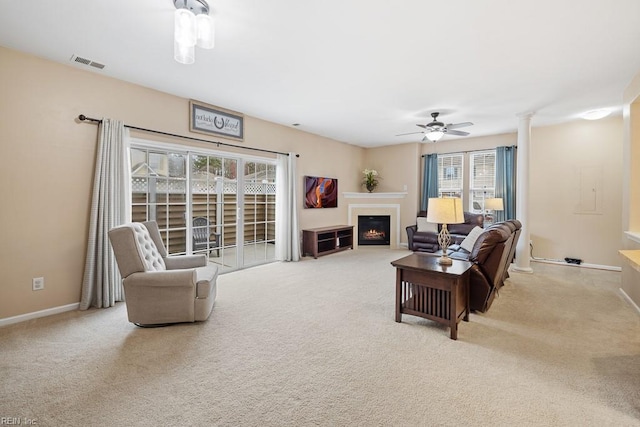 carpeted living room featuring a ceiling fan, a fireplace with flush hearth, visible vents, and baseboards