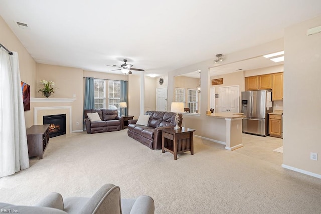 living room featuring baseboards, a fireplace with flush hearth, visible vents, and light colored carpet