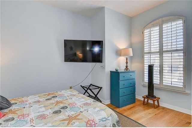 bedroom with multiple windows, baseboards, and wood finished floors