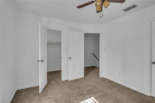 unfurnished bedroom featuring baseboards, visible vents, a walk in closet, and carpet flooring