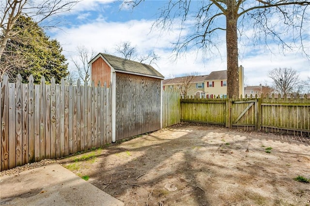 view of yard featuring an outbuilding, a shed, a fenced backyard, and a gate