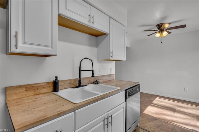 kitchen featuring baseboards, ceiling fan, stainless steel dishwasher, white cabinetry, and a sink