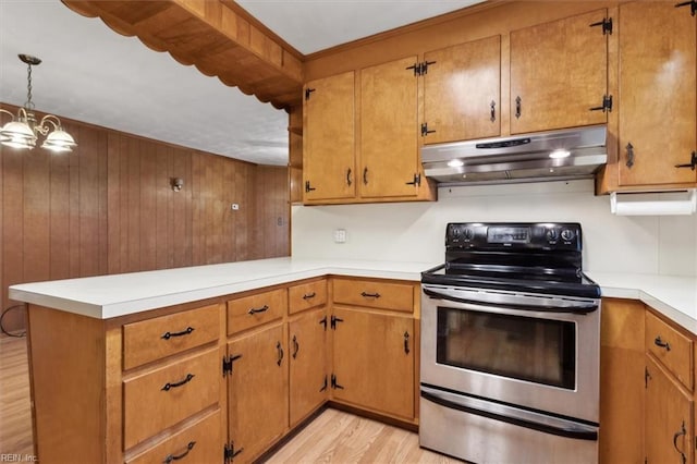 kitchen featuring under cabinet range hood, light wood-style floors, stainless steel range with electric stovetop, and light countertops