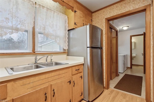 kitchen featuring a sink, freestanding refrigerator, crown molding, light wood finished floors, and light countertops