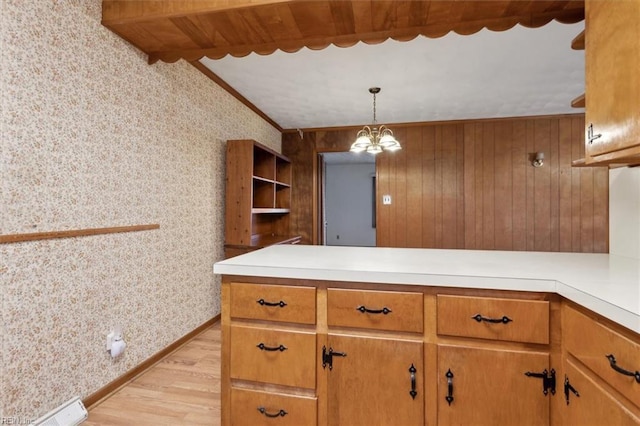 kitchen with wallpapered walls, light countertops, a peninsula, light wood-style floors, and brown cabinetry