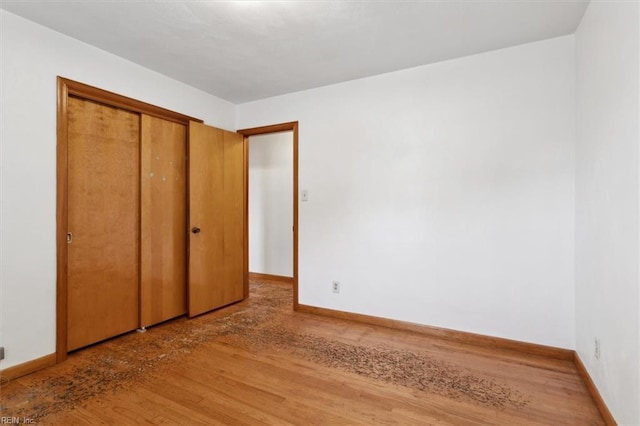 unfurnished bedroom with a closet, baseboards, and wood finished floors