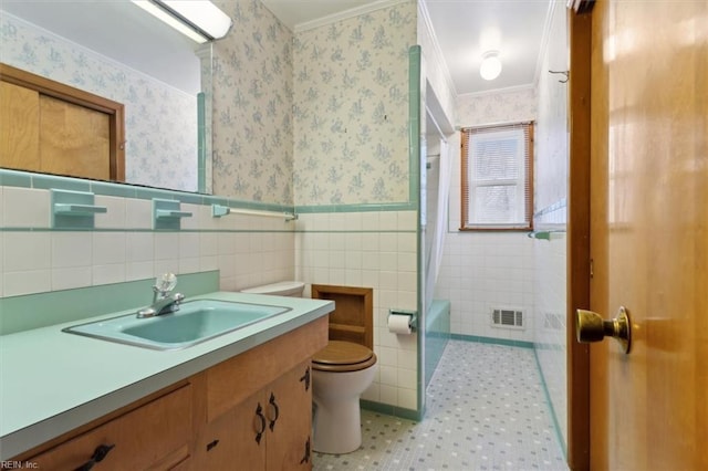 full bath featuring visible vents, a wainscoted wall, toilet, tile walls, and wallpapered walls