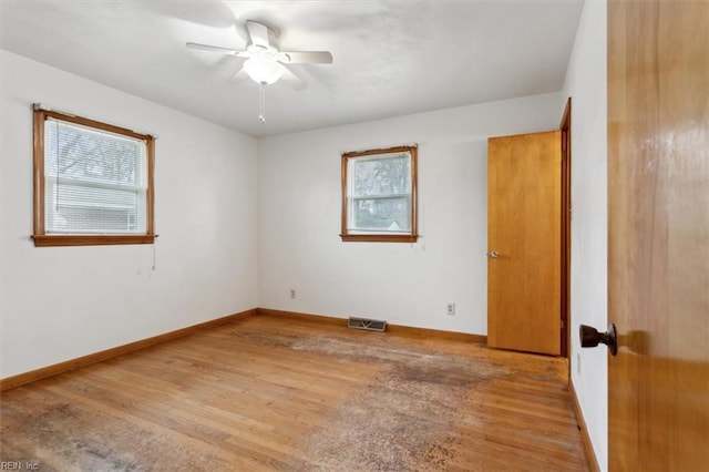 spare room with visible vents, ceiling fan, baseboards, and wood finished floors