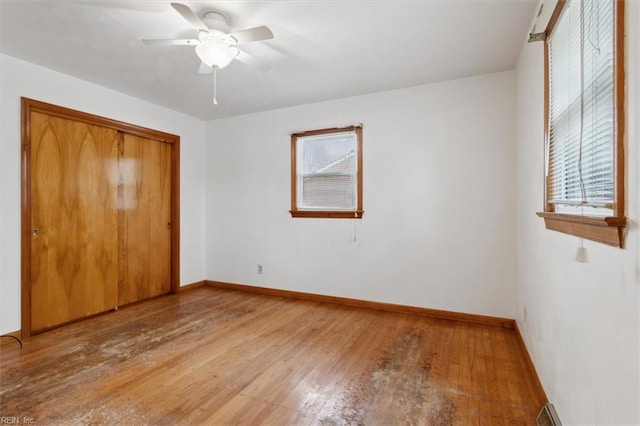 unfurnished bedroom featuring light wood-style flooring, baseboards, a closet, and ceiling fan