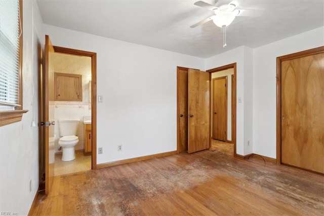 unfurnished bedroom featuring wood finished floors, baseboards, and connected bathroom