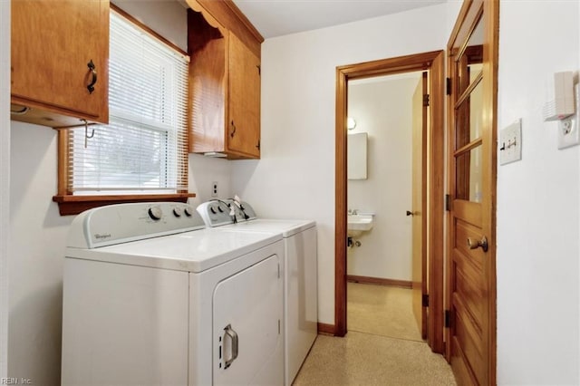 laundry area with a sink, baseboards, cabinet space, and separate washer and dryer