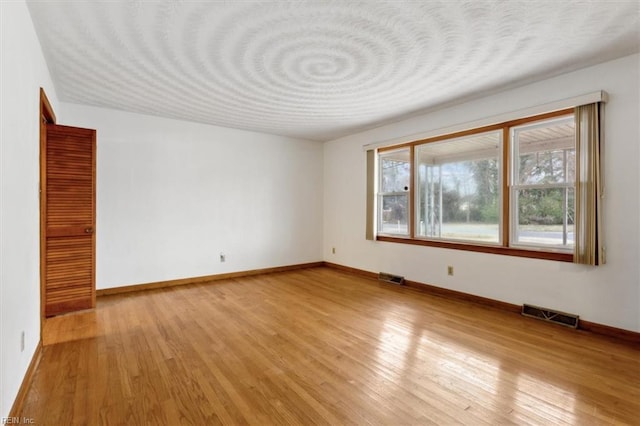 empty room with visible vents, baseboards, and light wood-style floors