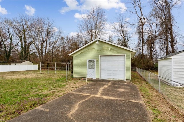 detached garage featuring concrete driveway and fence