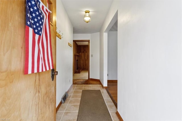 hall featuring tile patterned floors, baseboards, and visible vents