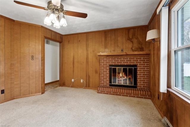 unfurnished living room with wooden walls, a brick fireplace, and carpet floors