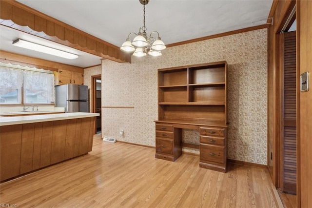 kitchen with wallpapered walls, light wood-style floors, an inviting chandelier, and freestanding refrigerator