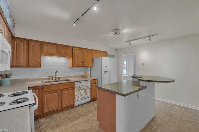 kitchen featuring white appliances, tasteful backsplash, brown cabinets, and a sink