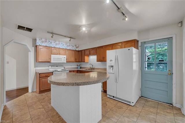 kitchen with white appliances, a kitchen island, a sink, visible vents, and tasteful backsplash