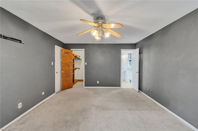 carpeted spare room with a ceiling fan and baseboards