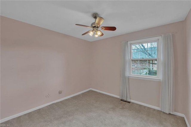 spare room with a ceiling fan, light colored carpet, and baseboards