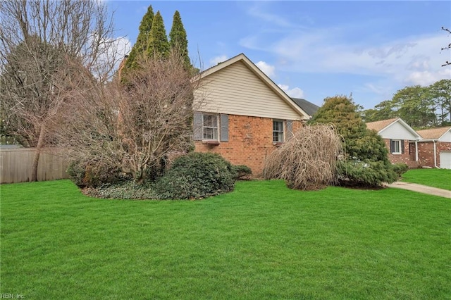 view of side of property with a yard, fence, and brick siding