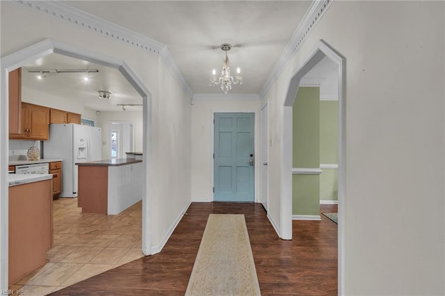 entrance foyer featuring arched walkways, crown molding, light wood-style flooring, and baseboards