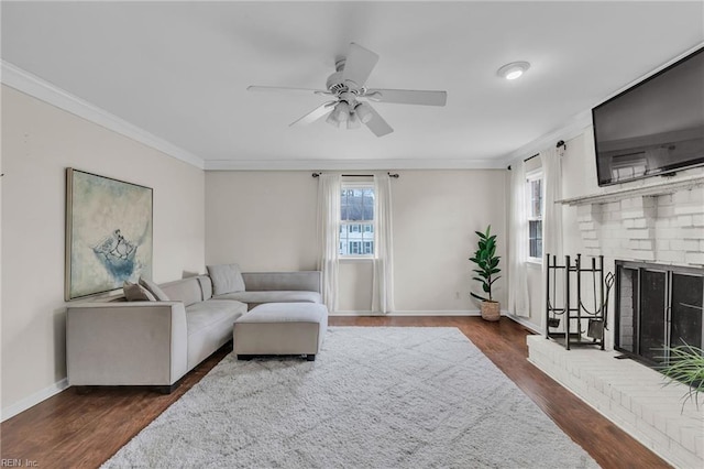 living area with ornamental molding, dark wood-type flooring, a brick fireplace, and baseboards