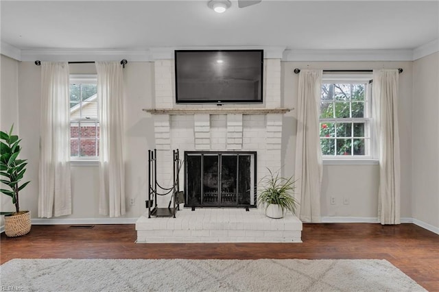 room details featuring ornamental molding, a brick fireplace, wood finished floors, and baseboards