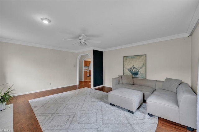 living room featuring ceiling fan, crown molding, arched walkways, and wood finished floors