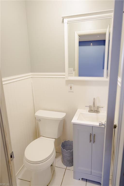 half bath with tile patterned flooring, vanity, and toilet