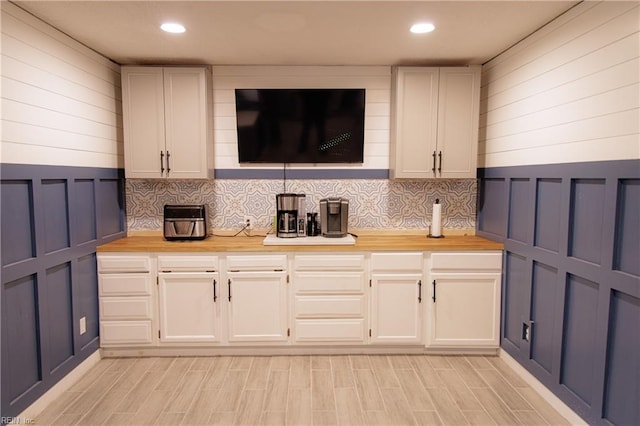 kitchen with backsplash, wood counters, and white cabinets