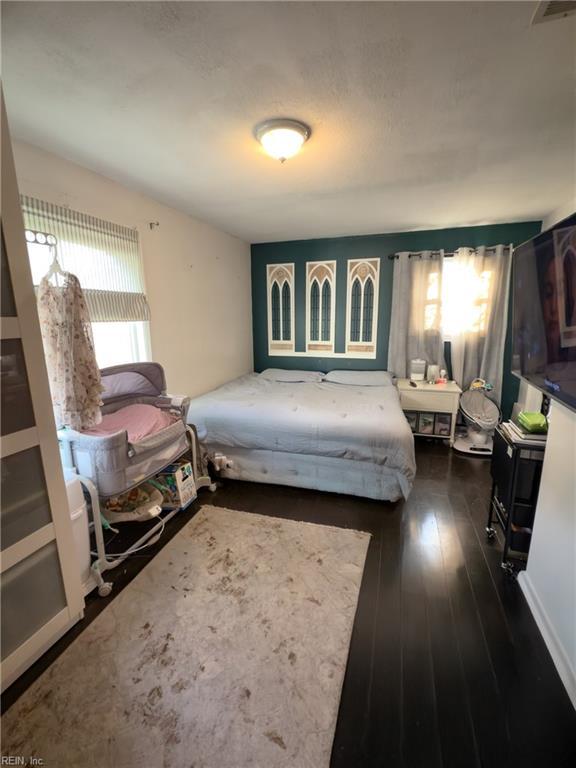 bedroom with multiple windows and dark wood finished floors