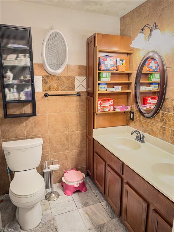 bathroom featuring toilet, vanity, and tile walls