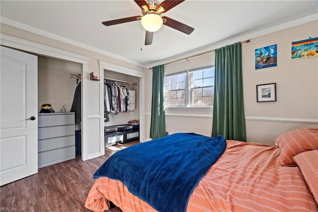 bedroom with dark wood-style floors, crown molding, multiple closets, and a ceiling fan