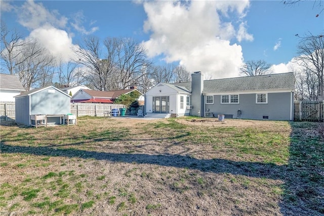 back of house with a lawn, a fenced backyard, a chimney, crawl space, and french doors