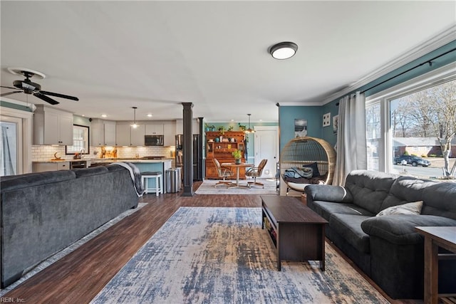 living area featuring ornamental molding, a ceiling fan, decorative columns, and dark wood-style floors