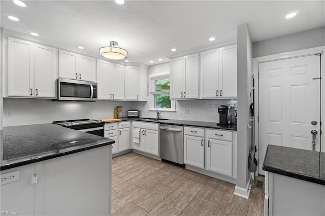 kitchen featuring appliances with stainless steel finishes, white cabinets, decorative backsplash, and dark stone counters