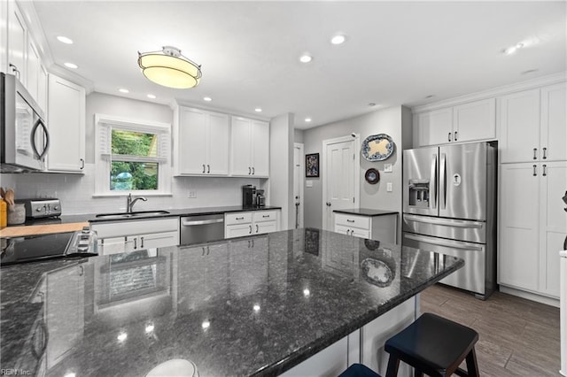 kitchen featuring stainless steel appliances, white cabinets, a sink, and tasteful backsplash