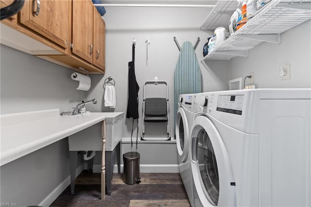 washroom with cabinet space, baseboards, dark wood-type flooring, and washing machine and clothes dryer