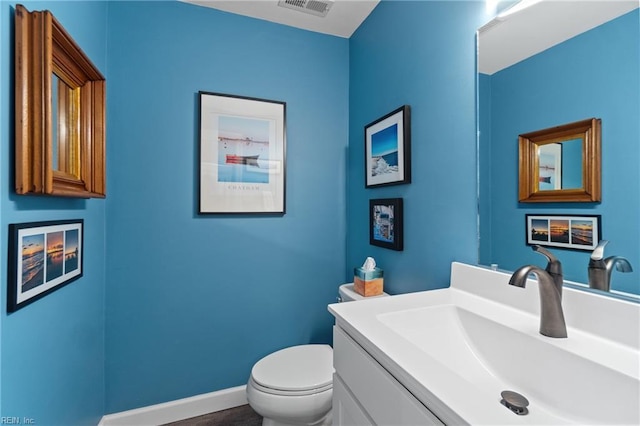 bathroom with baseboards, visible vents, vanity, and toilet