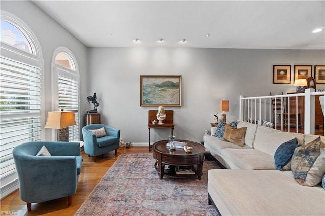 living area with baseboards, wood finished floors, and recessed lighting