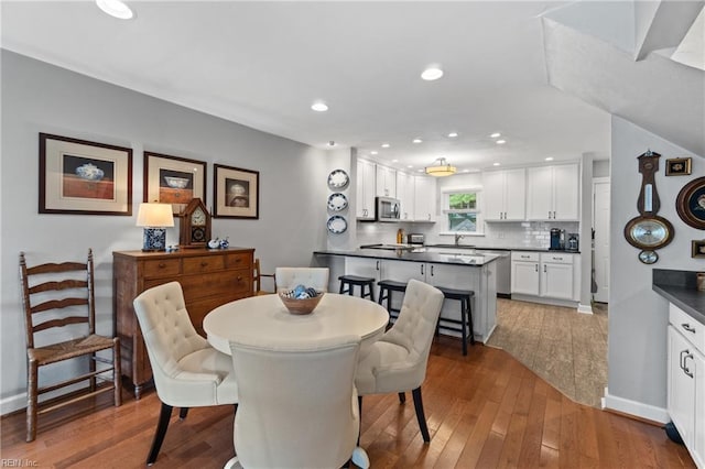 dining space with baseboards, hardwood / wood-style floors, and recessed lighting