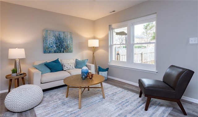 living area featuring baseboards, visible vents, and wood finished floors