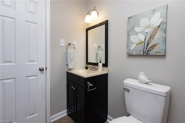 bathroom with vanity, toilet, and baseboards