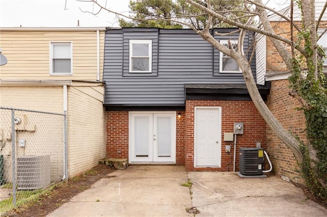 back of house featuring brick siding, cooling unit, and fence